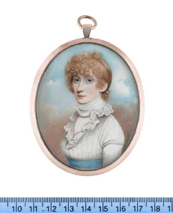 A lady, wearing white dress with frilled lace collar, sky blue sash, a white neck scarf tied tightly around her neck, her blonde hair upswept and curled by 
																	Charles Jagger
