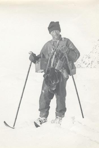 A pair of finnesko belonging to Levick; a full-length portrait of Levick laden with camera and instrument cases, with skis and wearing finnesko by 
																			George Murray Levick