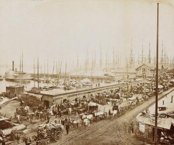 View of South Street, lower Manhattan, with clipper ships, ferry terminals and maritime workers posing for the camerman by 
																	George P Hall & Son