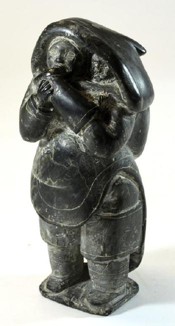 Standing woman with baby, softening a Kamik by 
																			 Ennutsiak