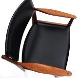 A pair of teak armchairs, upholstered in seat and back with black artificial leather by 
																			 Frem Rojle