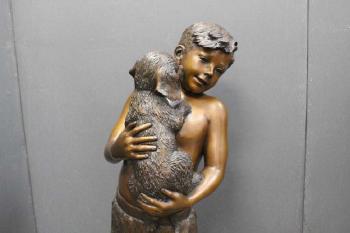 Large sculpture of a boy holding a dog by 
																			L Deane Trueblood