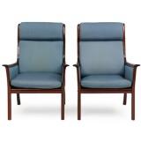 A pair of high backed easy chairs of dark stained mahogany by 
																			 P Jeppesen