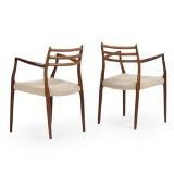 A pair of rosewood armchairs by 
																			 J L Moller