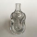 A clear glass vase decorated with four different faces by 
																			Bengt Edenfalk